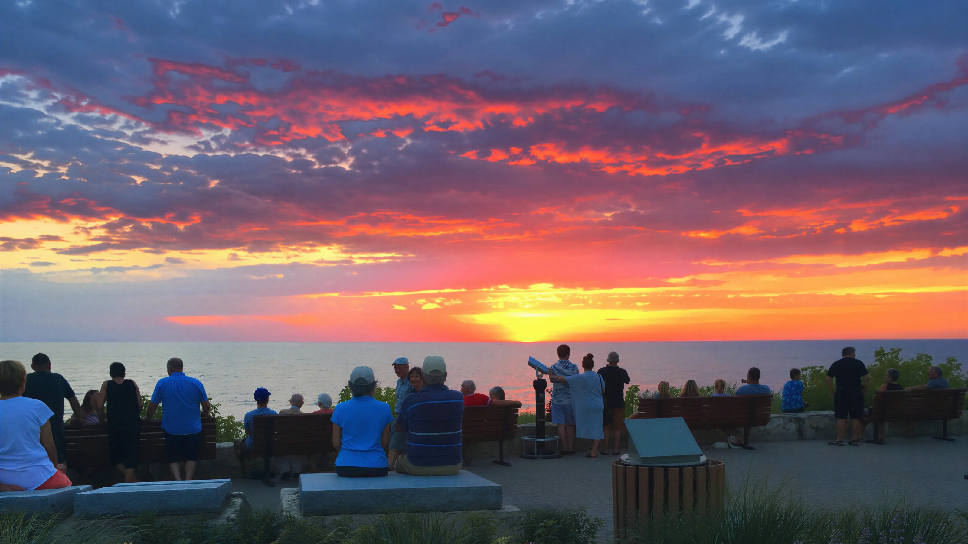People gathered on the shore at dusk to watch the sun set over Lake Huron